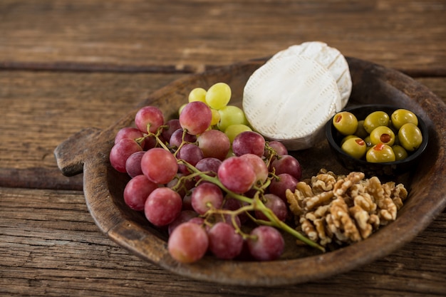 Kaas, druiven, olijven en walnoot op houten serveerschaal