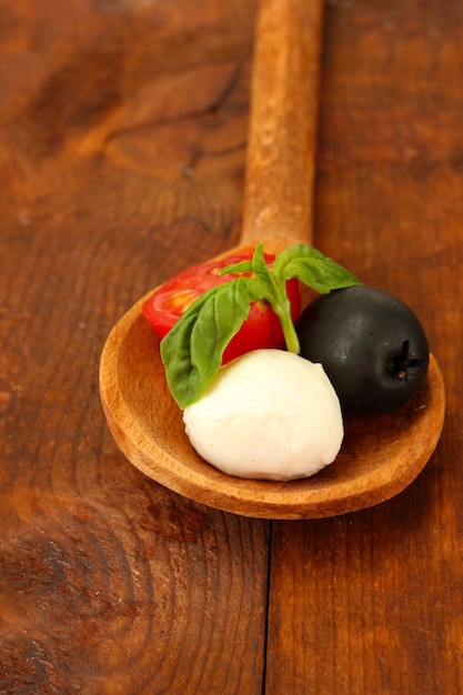 Foto kaas mozzarella met groenten in houten lepel op houten achtergrond close-up