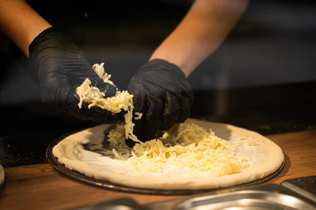 Foto kaas op het pizzadeeg strooien