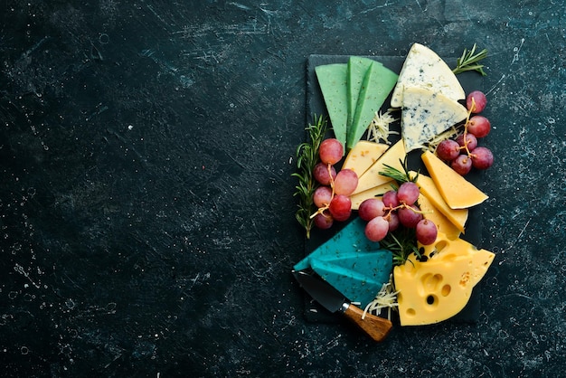 Kaas Set gekleurde kazen brie blauwe gorgonzola Parmezaanse kaas en maasdam op een zwarte stenen achtergrond Gratis kopie ruimte Bovenaanzicht