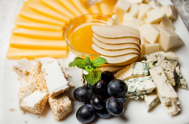 Kaas van verschillende soorten en druiven op een bord. Brie, camembert, Parmezaanse kaas, harde kaas. Kaas plankje