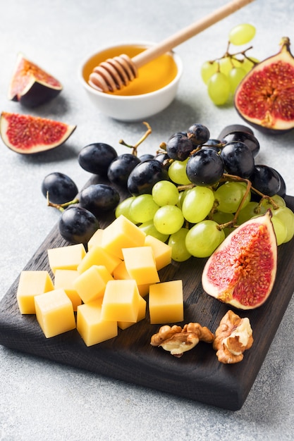 Kaasblokjes, vers fruit vijgen druiven Honing walnoot op houten snijplank. Selectieve aandacht. Detailopname.