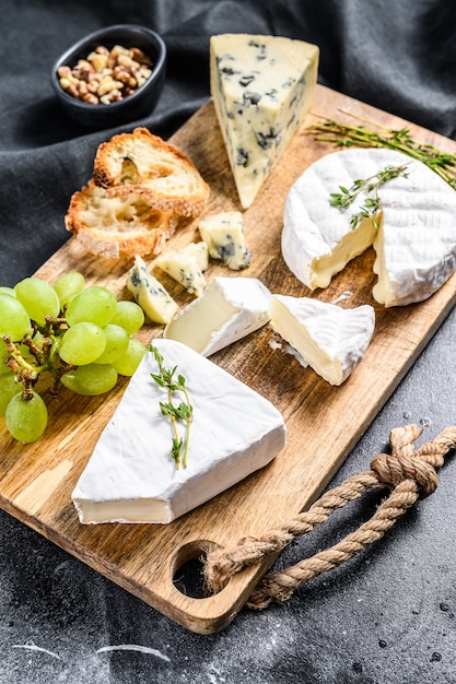 Kaasbordje met camembert, brie en blauwe kaas met druiven en walnoten. Zwarte achtergrond. Bovenaanzicht