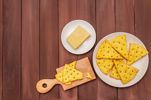 Foto kaascrackers, zout snackconcept. koekjes, stuk kaas, snijplank.