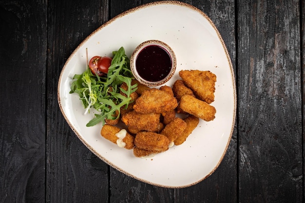 Kaasfrietjes met kruiden en saus op borden op een houten tafel