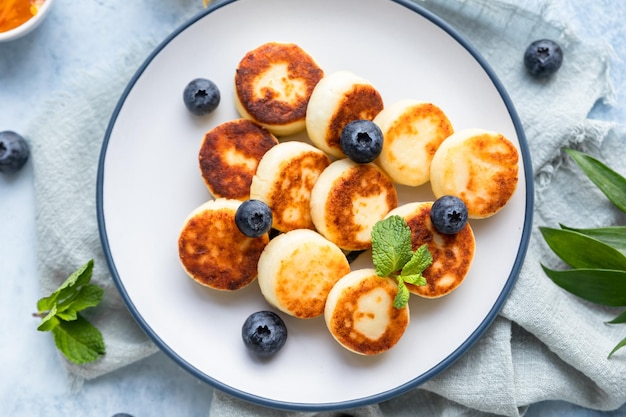 Foto kaaspannenkoekjes of syrniki met bosbessenphysalis en yoghurt gezond en lekker ontbijt