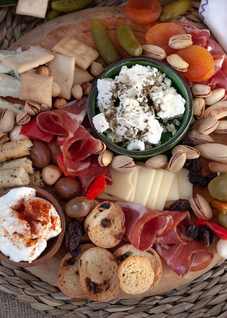 Kaasplank met aperitiefselectie, kaasvariëteit, gezouten vlees, crackers, olijven. Kleurrijke maaltijd. Bovenaanzicht.