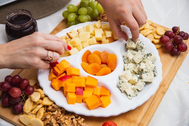 Kaasplankje met verschillende hapjes op tafel. Aardbeien-, abrikozen-, druiven- en graankaasschotels op tafel