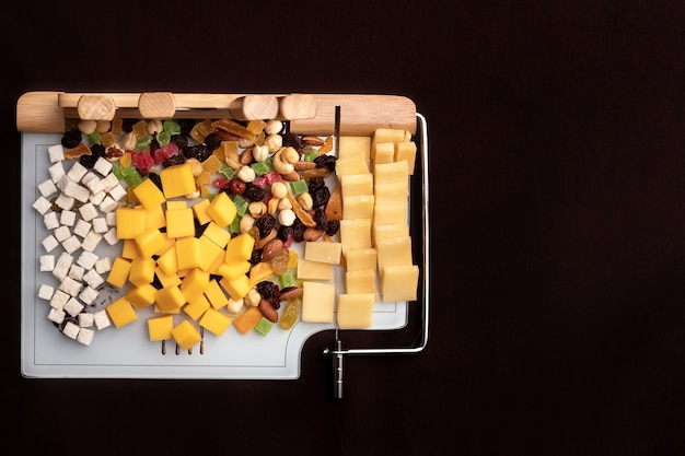 Kaasschotel met verschillende kazen en gedroogd fruit op een gesneden bord met apparaten om te snijden