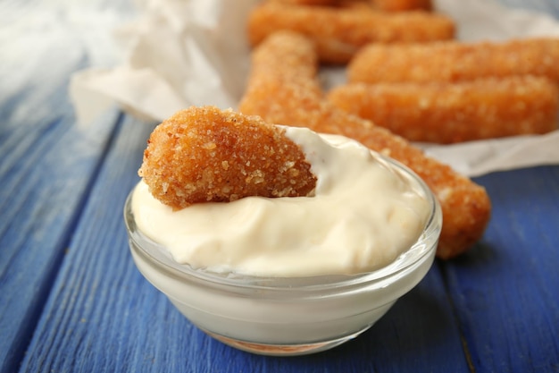 Kaasstokje in kom met saus op tafel