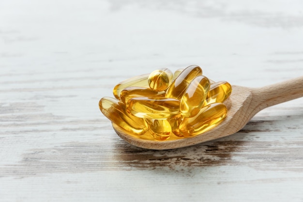 Kabeljauwleverolie omega 3 gelcapsules op een lepel op houten achtergrond