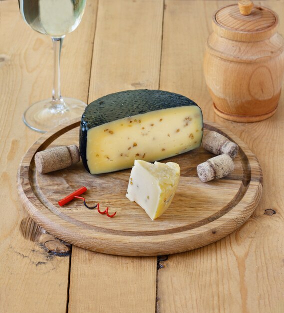 Photo kachotta cheese on a wooden board on a wooden background with wine in a glass and honey