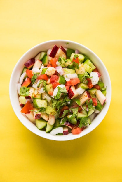 Kachumber OR Indian Green Salad also known as Koshimbir. Served in a bowl over moody background. Selective focus