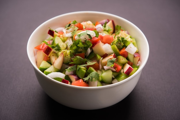 Kachumber OR Indian Green Salad also known as Koshimbir. Served in a bowl over moody background. Selective focus