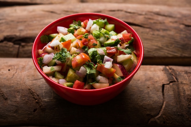 Kachumber OR Indian Green Salad also known as Koshimbir. Served in a bowl over moody background. Selective focus