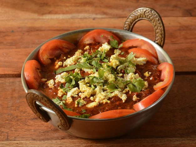 Foto il paneer kadai è un famoso piatto indiano servito su un fuoco selettivo di fondo in legno rustico