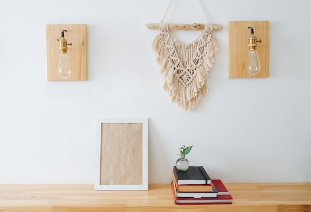 Foto kadermodel op de plank naast een stapel boeken onder een macraméhanger