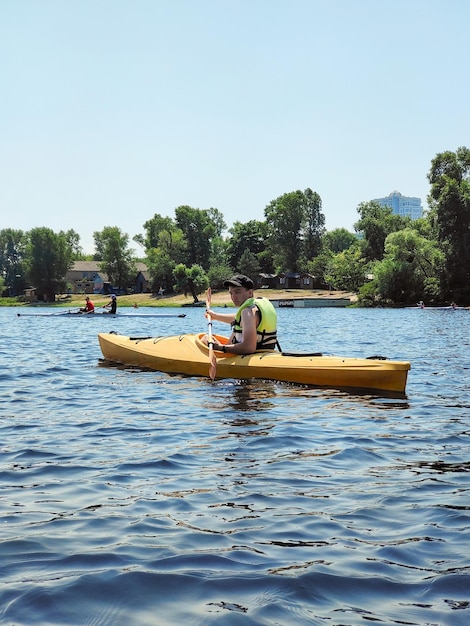 Kajakken Een jonge man is aan het kanoën op een brede rivier en glimlacht Zijaanzicht Sporttoerisme en actief