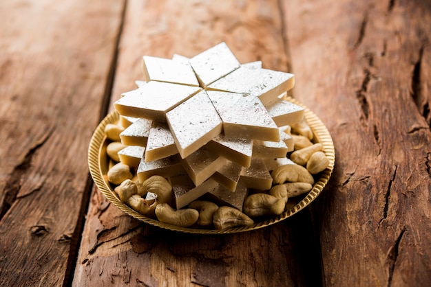 Kaju Katli is een Indiaas snoepje in de vorm van een diamant, gemaakt van cashewsuiker en mava, geserveerd in een bord op een humeurig oppervlak. selectieve focus