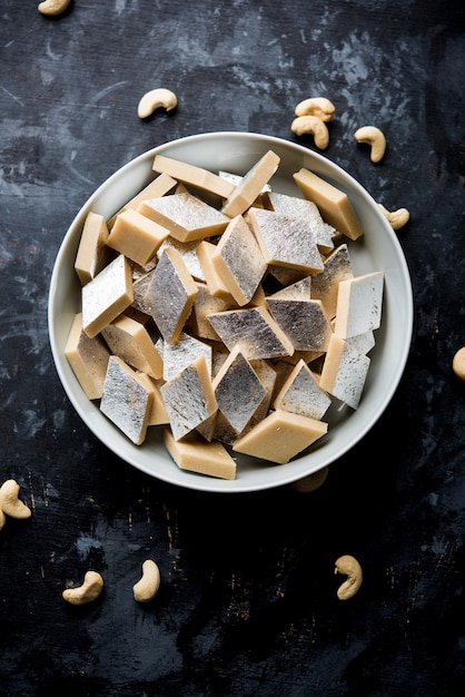 Kaju Katli is een Indiaas snoepje in de vorm van een diamant, gemaakt van cashewsuiker en mava, geserveerd in een bord op een humeurig oppervlak. selectieve focus