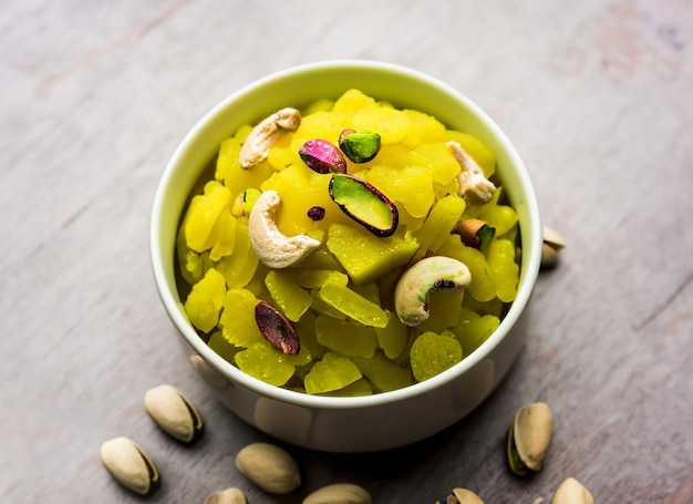 Kaju Katli is a traditional Indian Diamond shaped sweet or Mithai made using cashew paste sugar and mava or Khoya served in a wooden plate over dark background cashew barfi Copy space