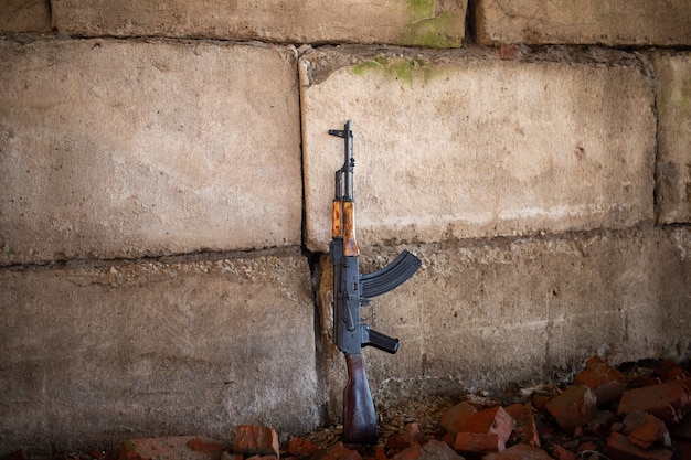 A Kalashnikov rifle on the brick background of the war