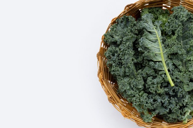 Kale leaves in bamboo basket on white background. Top view