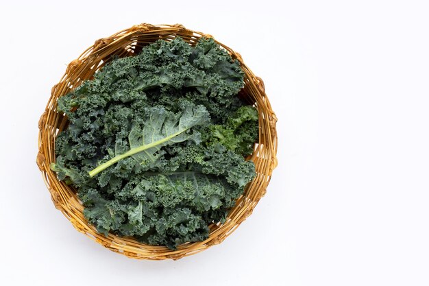 Kale leaves in bamboo basket on white background. Top view