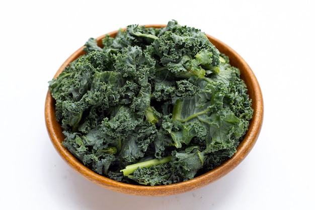 Kale leaves in wooden bowl on white background.