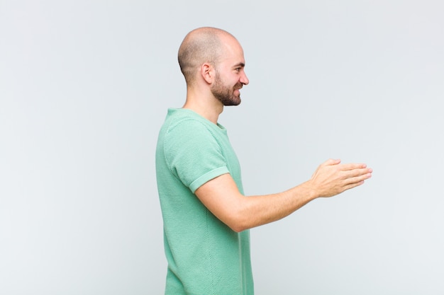 Kale man glimlachend en groet met een handbeweging