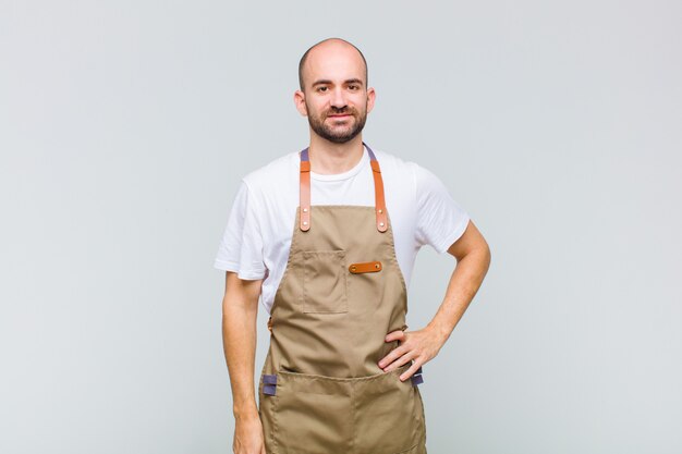 Kale man glimlachend gelukkig met een hand op de heup en zelfverzekerd, positief, trots en vriendelijke houding