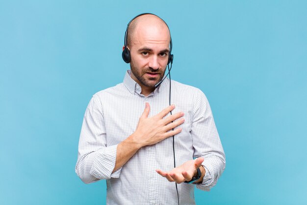 Kale man voelt zich gelukkig en verliefd, glimlachend met de ene hand naast het hart en de andere vooraan gestrekt