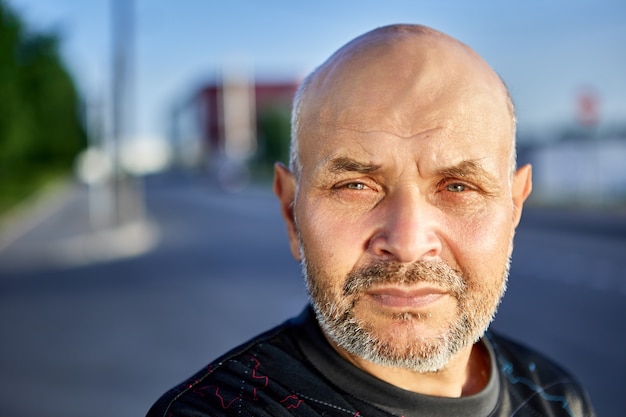 Kale oudere man met grijze stoppels voor stadsstraat