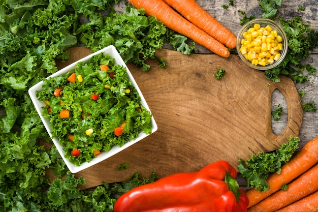 Kale salad in white bowl on wooden table