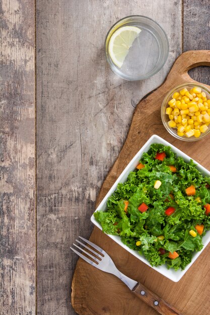 Kale salad in white bowl on wooden table