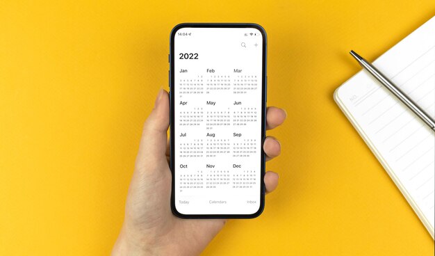 Kalender 2022-app op smartphonescherm. Hand met mobiele telefoon. Om te doen, nieuwjaarsplanning concept foto