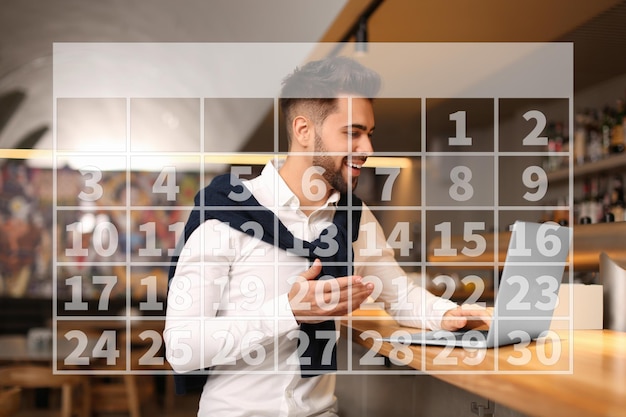 Kalender en man aan het werk met laptop in café