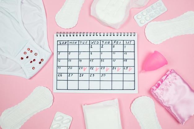 Kalender foto ondergoed menstruatie cup maandverband op geïsoleerde pastel roze achtergrond het concept van menstruatie vrouwen creatieve dagen