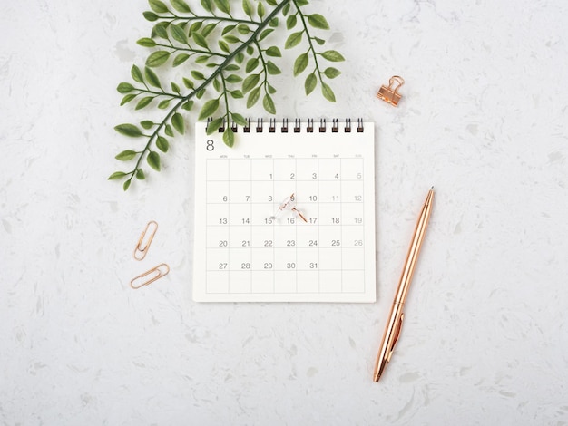 Kalender met roségouden pen en groen blad