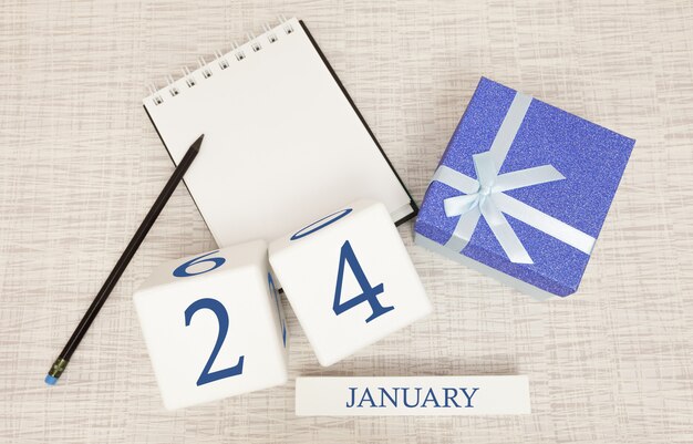 Kalender met trendy blauwe tekst en cijfers voor 24 januari en een geschenk in een doos