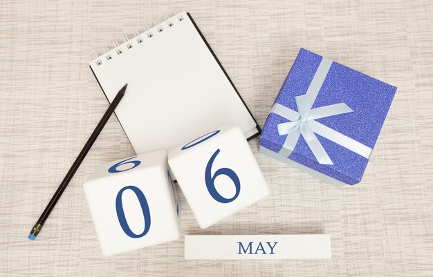 Kalender met trendy blauwe tekst en cijfers voor 6 mei en een geschenk in een doos.