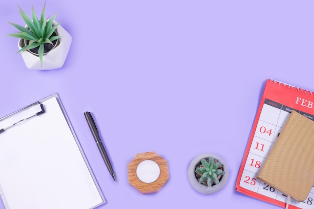 Kalender Open notebook pen met alarm en groene bloempot op paarse achtergrond Business onderwijs werkconcept