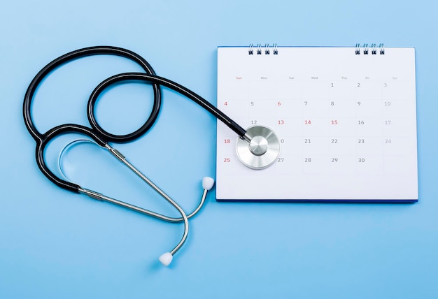 Kalender, stethoscoop, op een blauwe achtergrond, gezondheidszorgconcept.