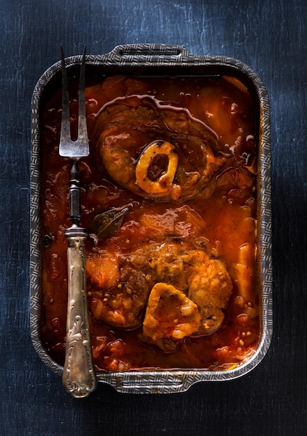 Kalfsschenkel gekookt met tomaten, wortelen en ui. Osso buco.