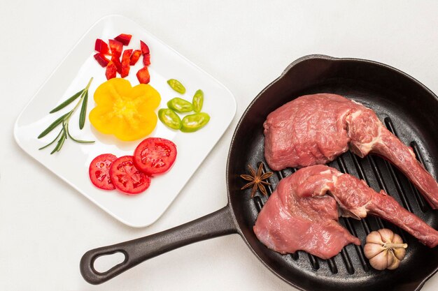 Kalfsvlees met knoflook en steranijs in de pan gesneden tomaten en paprika's op een wit bord