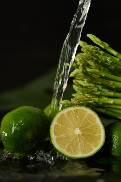 kalk en asperges wassen met een stroom water, water uit de kraan op de groenten gieten Close-up