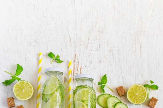 Foto kalk, komkommer, peterselie limonade in flessen op een witte pagina