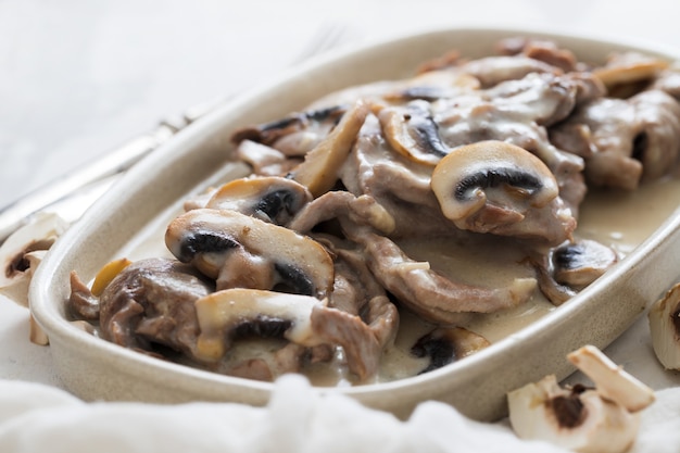 Kalkoen met champignons en saus op schotel op keramiek