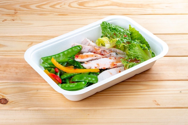 Kalkoenfilet met verse groenten Gezond dieet Afhaalvoedsel Eco-verpakking op een houten achtergrond