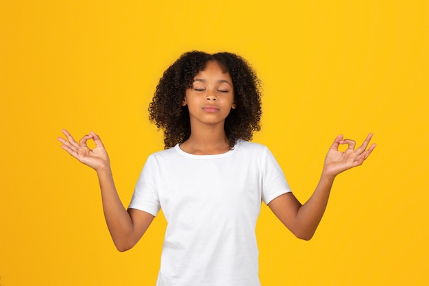 Kalm adolescent Afro-Amerikaans meisje in wit t-shirt mediteert geniet van stilte